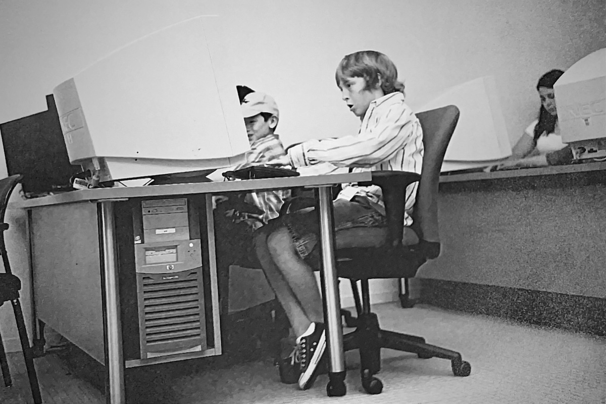 A young Duncan Crawbuck intently focused on typing at a computer with a large CRT monitor.